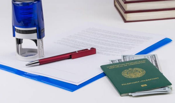 Uzbekistan passport with US dollars on the background of documents and contract. Concept - briber and corruption